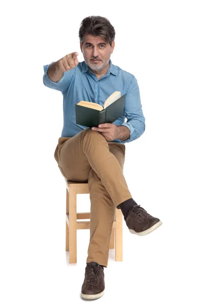 Hombre casual confiado leyendo un libro y señalando hacia adelante —  Fotos de Stock