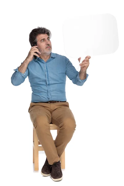 Hombre ansioso hablando por teléfono y mirando la burbuja del habla — Foto de Stock