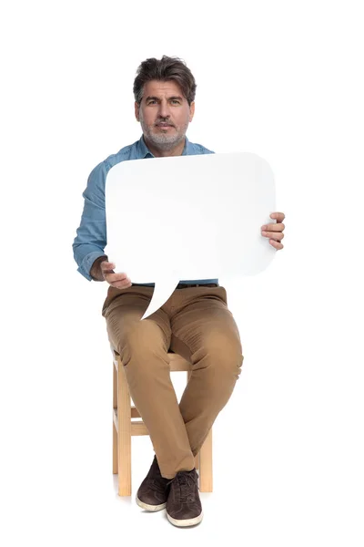 Ernst aussehender lässiger Mann, der eine Sprechblase hält und f — Stockfoto