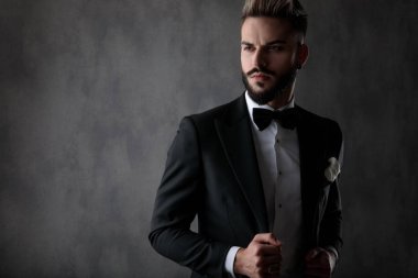 businessman standing and fixing jacket while looking away