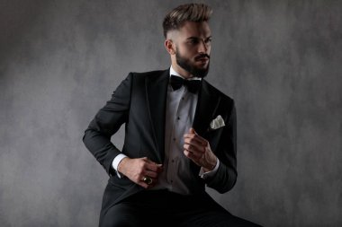 businessman fixing his jacket while looking aside with cool atti