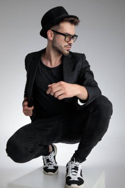 dramatic young man holding elbow in a fashion pose