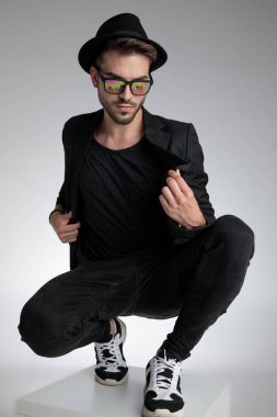 dramatic cool guy holding coat and crouching in a fashion pose