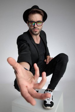 cool young guy holding hand close to the camera in a fashion pos