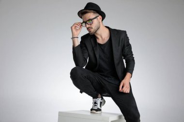 cool dramatic guy fixing glasses and looking to side