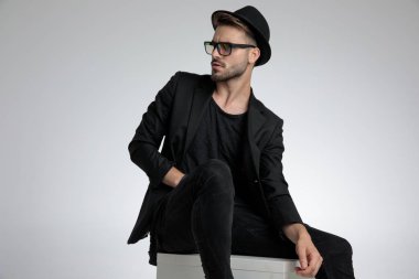 dramatic fashion guy looking to side and holding leg in a fashio