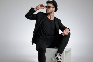 cool dramatic guy fixing glasses and looking to side