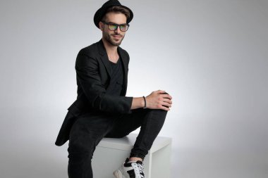 happy cool guy holding hand on knee and smiling