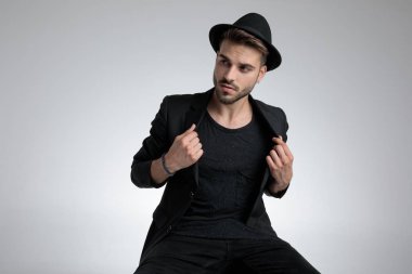 dramatic cool guy pulling black coat and looking to side