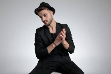 cool young man in black coat touching palms