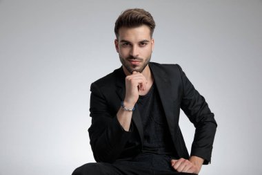 cool fashion guy holding hand to chin and posing