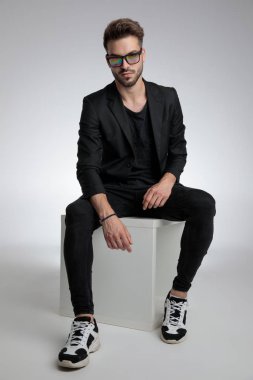 cool dramatic guy sitting in a fashion pose