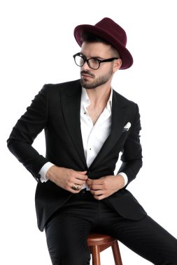 businessman with burgundy hat sitting and fixing jacket