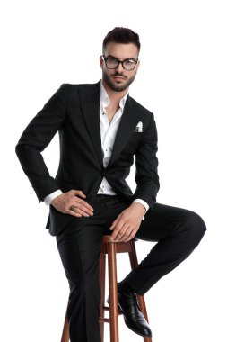 charming young elegant man sitting on a stool