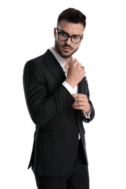 businessman standing and fixing sleeve while looking down