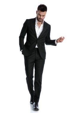 İş adamı zarif bir şekilde yürüyor ve aşağıya bakıyor.