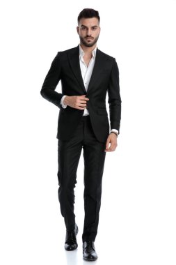 Bir eli bol, bir eli ceketli işadamı yürüyor.