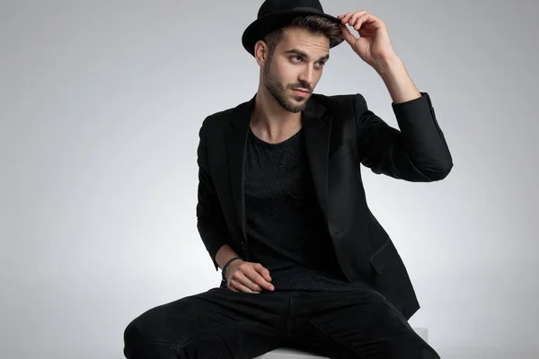 Cool fashion man holding hat and looking to side — Stock Photo, Image