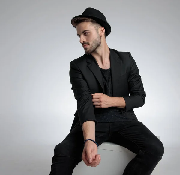 cool fashion guy wearing hat and holding elbow in a fashion pose