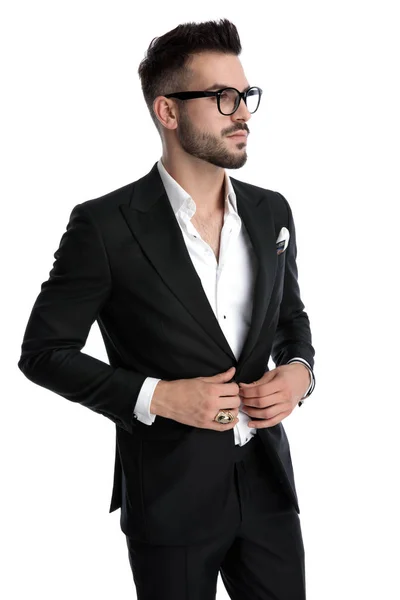 Empresário de pé e olhando para o lado enquanto fixa jaqueta serio — Fotografia de Stock