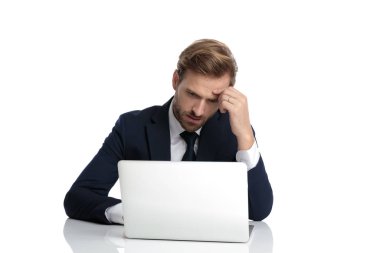 Lacivert takımlı dalgın genç işadamı e-postaları okuyor.