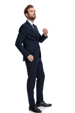 Lacivert takımlı düşünceli genç adam yukarı bakıyor.