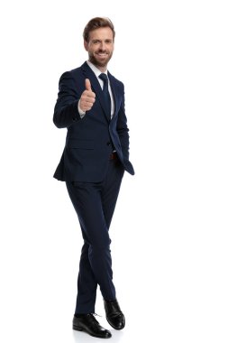 Mutlu genç işadamı gülümsüyor ve baş parmak işareti yapıyor.