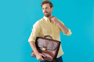 Charming casual man adjusting his collar and holding a briefcase
