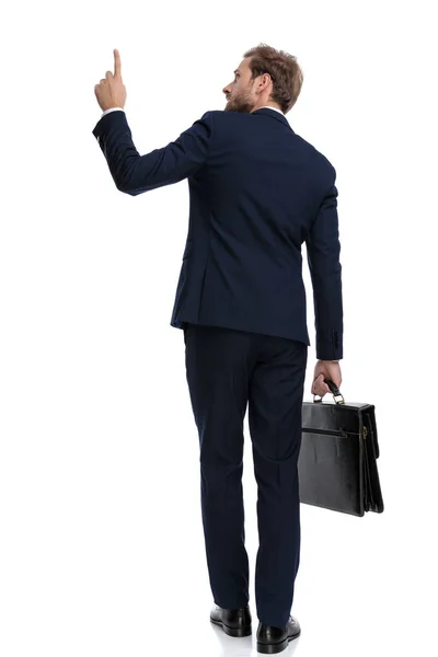Giovane uomo d'affari in tuta blu navy puntando il dito e tenendo — Foto Stock