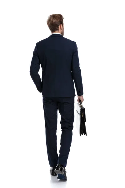 Sexig ung affärsman i marinblå kostym håller resväska — Stockfoto