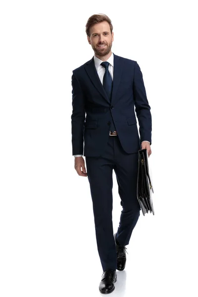 Sexy joven hombre de negocios en azul marino traje celebración maleta y sm —  Fotos de Stock