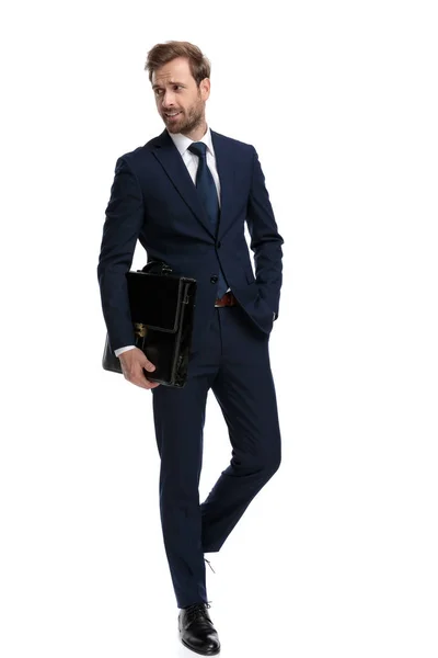 Sexy young man in navy blue suit holding suitcase in fashion pos — 스톡 사진