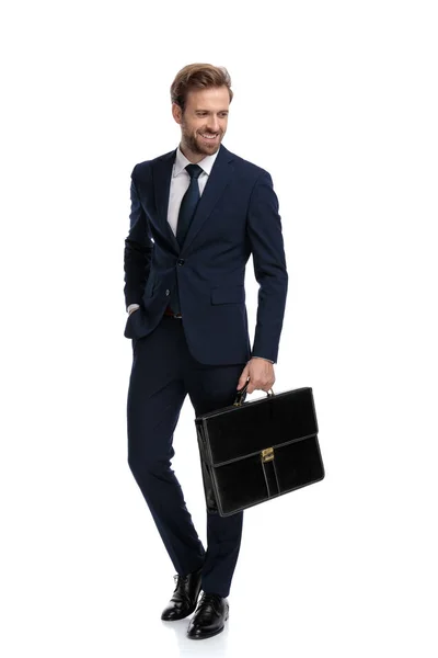 Glimlachende jonge zakenman in marine blauw pak met koffer — Stockfoto