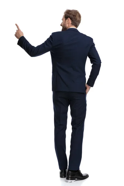 Hombre de negocios sonriente en traje azul marino apuntando de un lado a otro — Foto de Stock