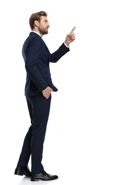 Giovane uomo d'affari in tuta blu navy punta dito a fianco — Foto Stock