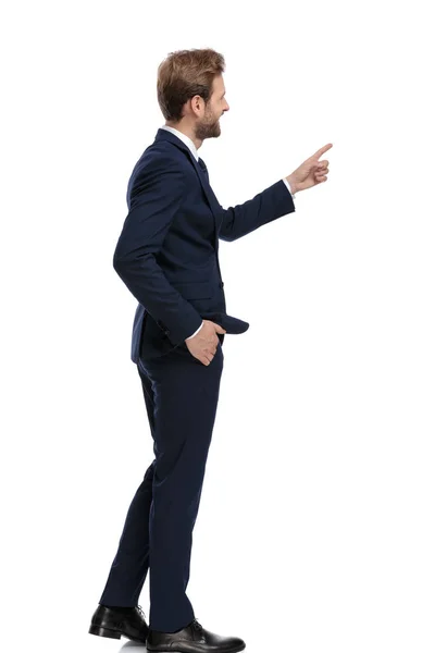 Glad affärsman i marinblå kostym pekar finger — Stockfoto