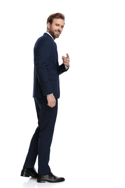 Young businessman in navy blue suit pointing finger and smiling — Stock Photo, Image