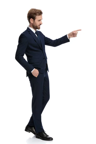 Young businessman in navy blue suit pointing finger to side — Stock Photo, Image