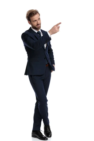 Giovane uomo d'affari in tuta blu navy puntando il dito e mostrando — Foto Stock