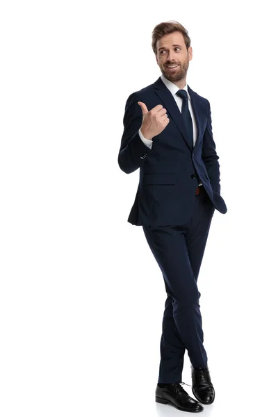 Счастливый бизнесмен смотрит в сторону и делает большие пальцы вверх знак — стоковое фото