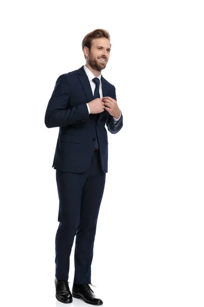 Gelukkig zakenman in marine blauw pak regelen stropdas — Stockfoto