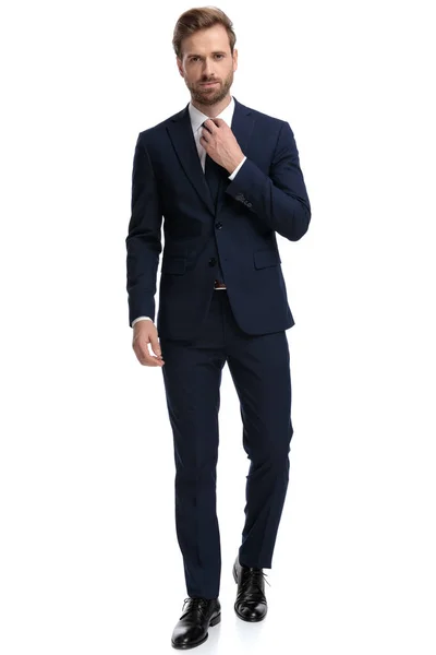 Уверенный в себе бизнесмен в синем костюме, регулирующий галстук — стоковое фото