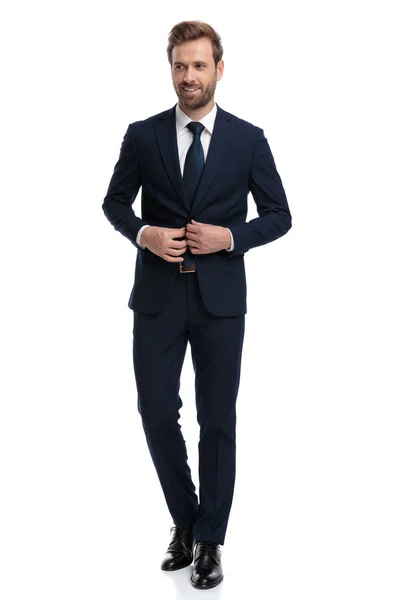 Happy young businessman in navy blue suit arranging coat — 스톡 사진