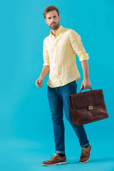 Determined casual man holding a briefcase and walking forward — Stok fotoğraf