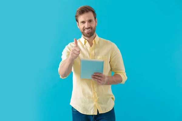 Casual man giving a thumbs up and holding a tablet — Stok fotoğraf