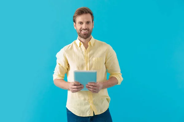 Gelukkig casual man die een tablet vasthoudt en vooruit kijkt — Stockfoto