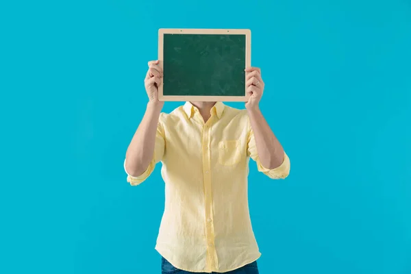 Young casual man hiding his face behind a blackboard — Stock Photo, Image