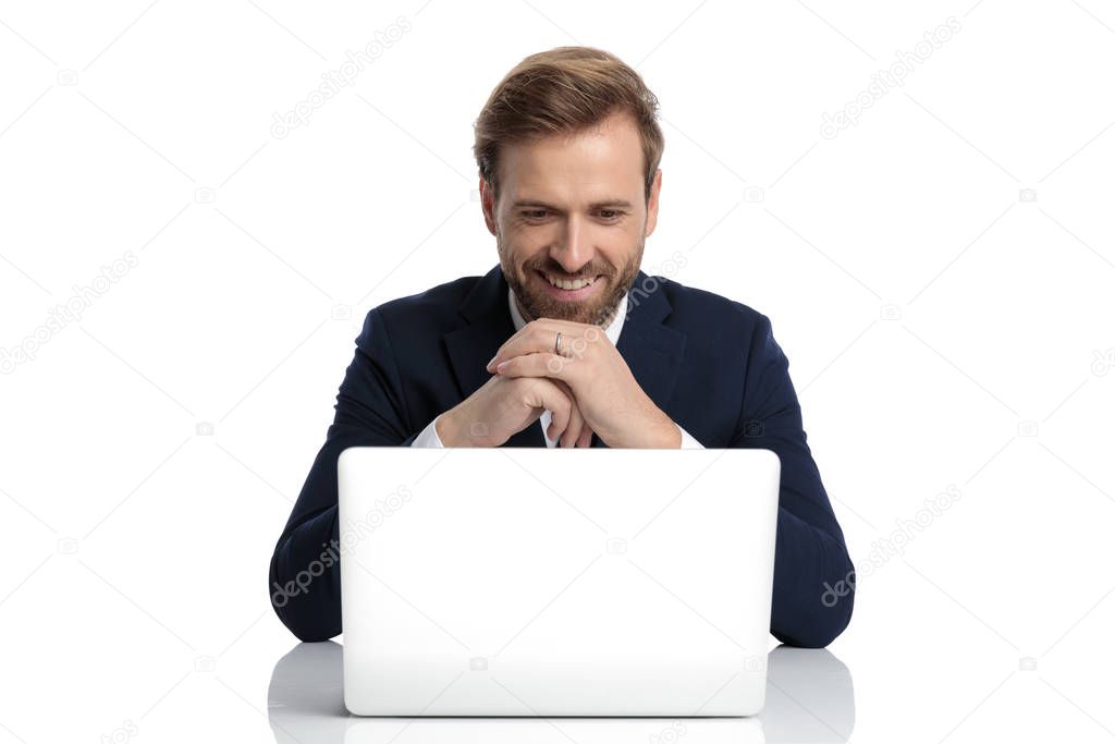 young businessman in navy blue suit reading emails and smiling