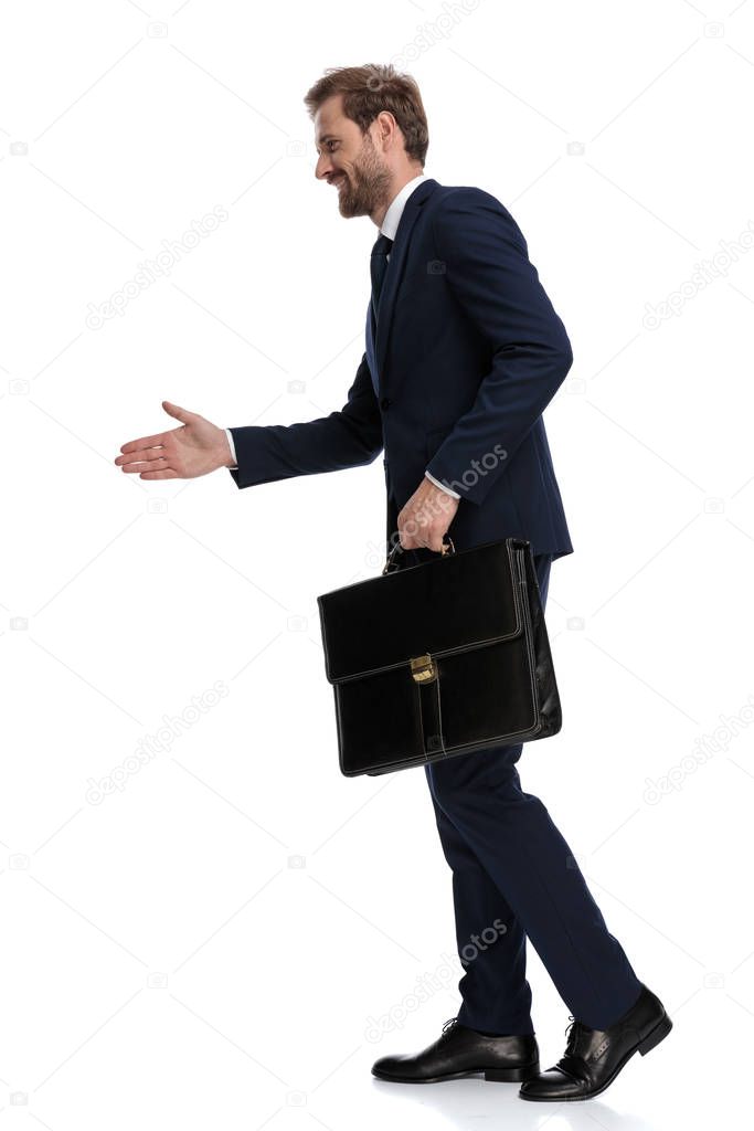 happy young businessman holding suitcase and shaking hand