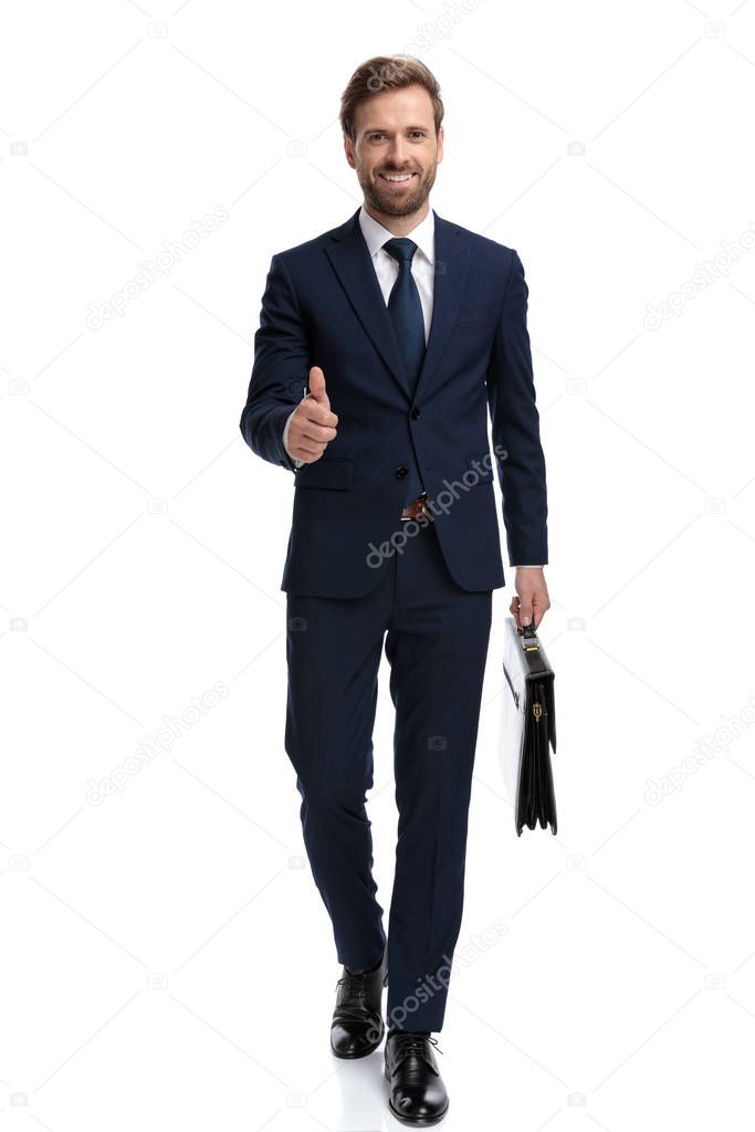 happy businessman holding suitcase and making thumbs up sign